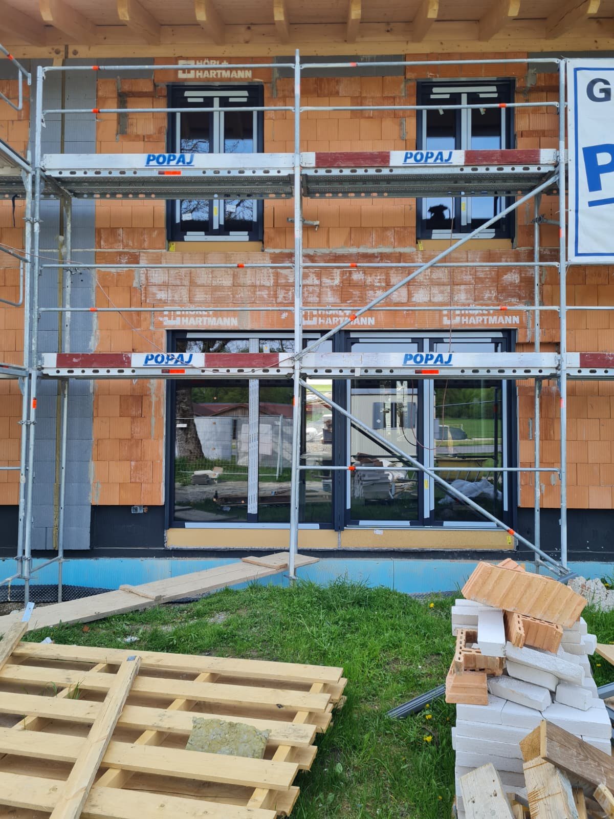 Anthrazitfarbene Fenster und große Türelemente während der Montage an einem Neubau