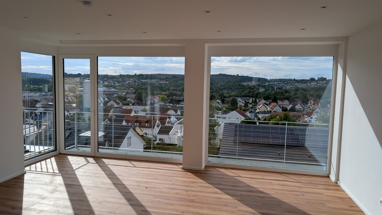Große bodentiefe Fenster und Eckverglasung in einem fertiggestellten Wohnraum mit Holzboden